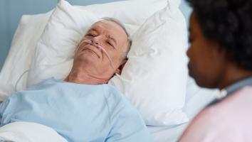 een verpleegkundige helpt een patiënt in een ziekenhuisbed