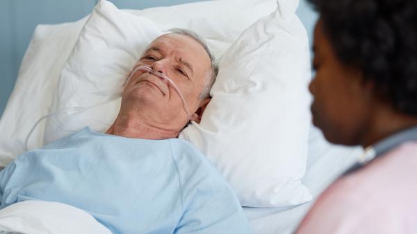 een verpleegkundige helpt een patiënt in een ziekenhuisbed