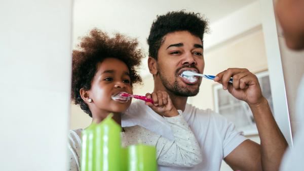 Vader en kind poetsen samen tanden