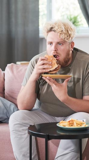 Man zit op de bank fastfood te eten