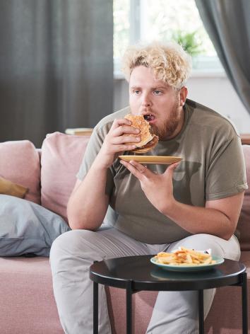 Man zit op de bank fastfood te eten