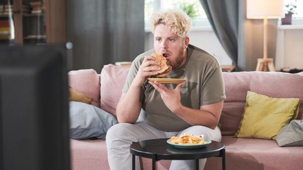 Man zit op de bank fastfood te eten