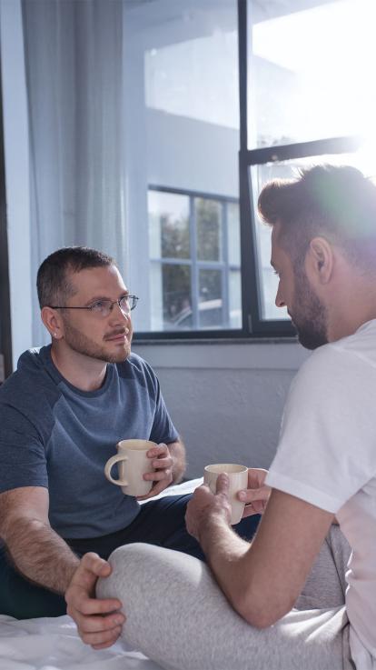 een homostel praat met elkaar op bed
