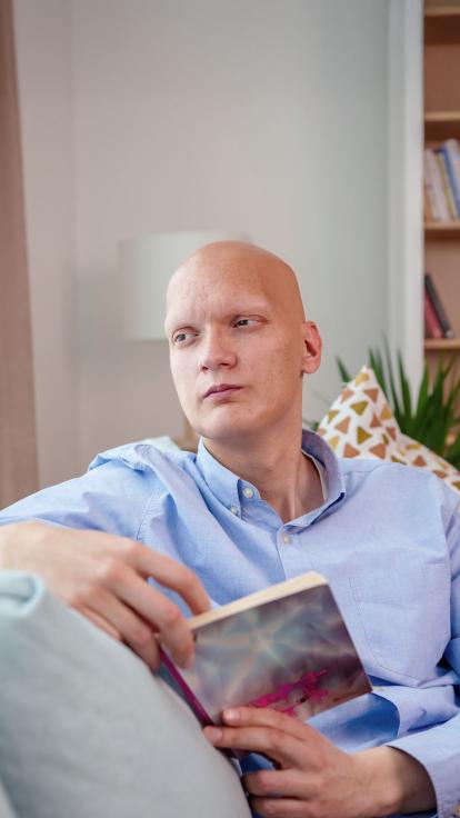 een man met kanker staart voor zich uit met een boek in z'n hand