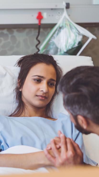 een man troost zijn vrouw die in een ziekenhuisbed ligt