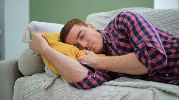 een vermoeide man slapend op de bank