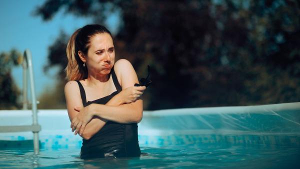 Een vrouw heeft het koud in het zwembad.