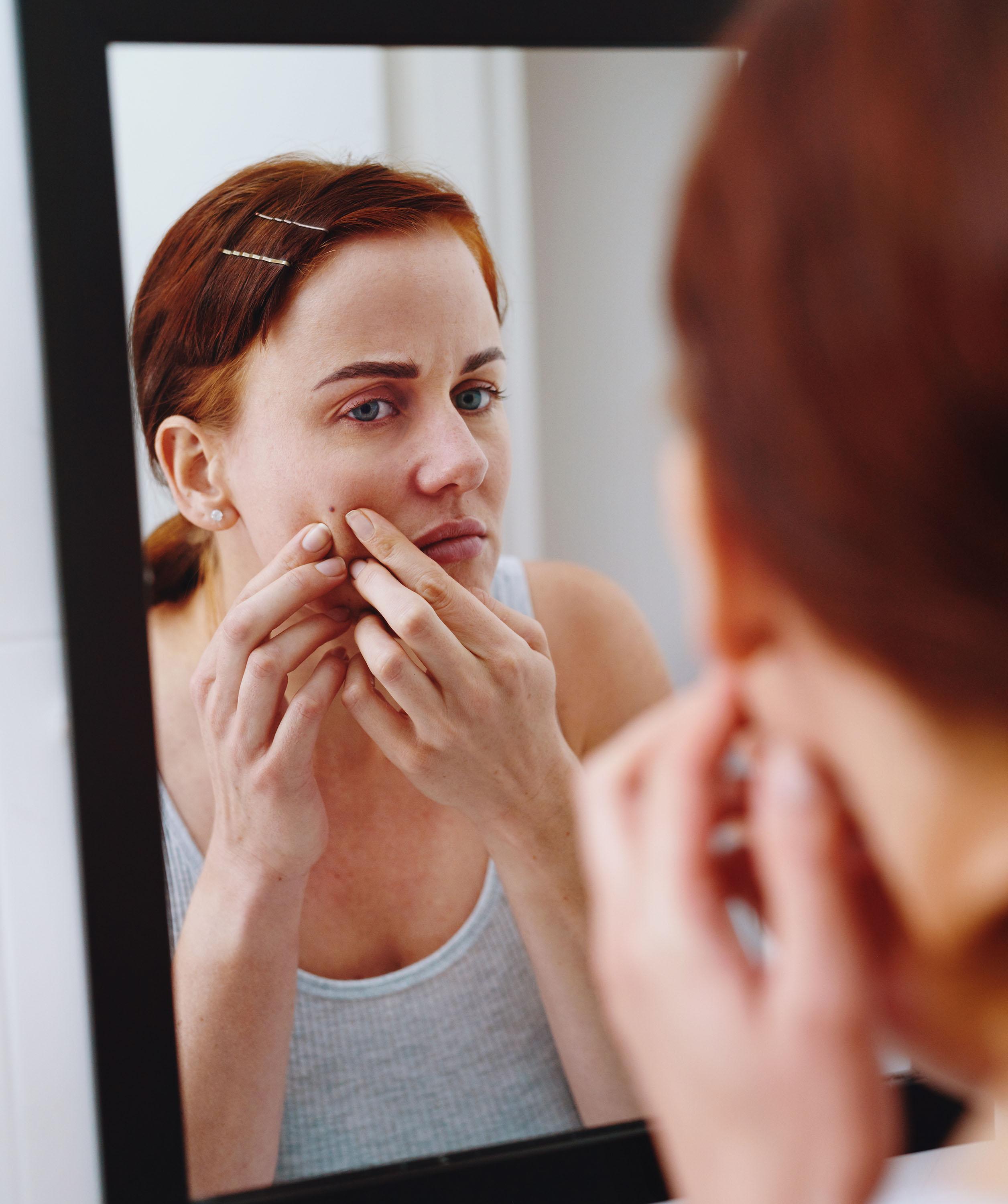 een vrouw bekijkt een moedervlek in de spiegel