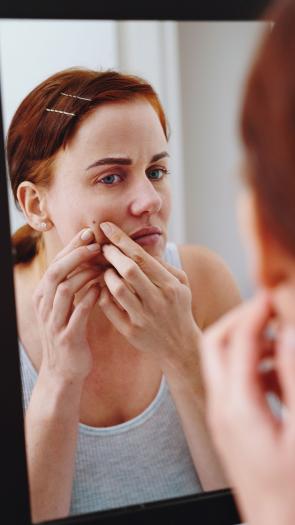 een vrouw bekijkt een moedervlek in de spiegel