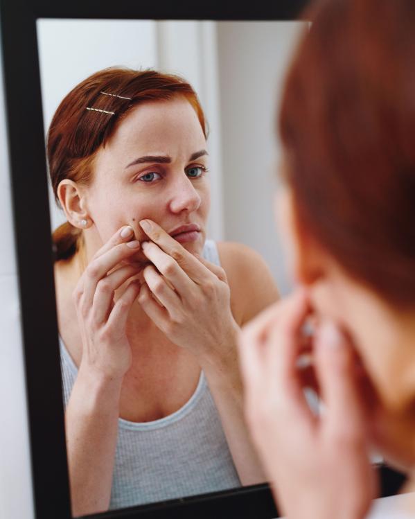 een vrouw bekijkt een moedervlek in de spiegel