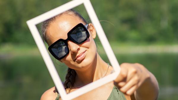een vrouw houdt een wit frame voor haar gezicht