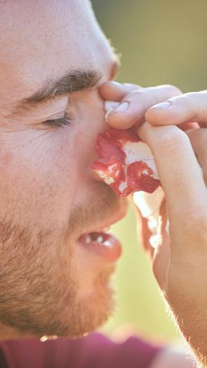 een man met een bebloed zakdoekje bij zijn neus