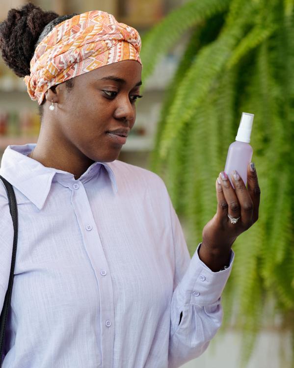 een vrouw kijkt naar een flesje met zonnebrandcrème
