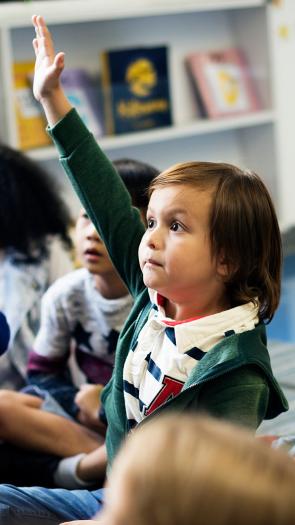 Kinderen in een kleuterklas steken hun vinger in de lucht
