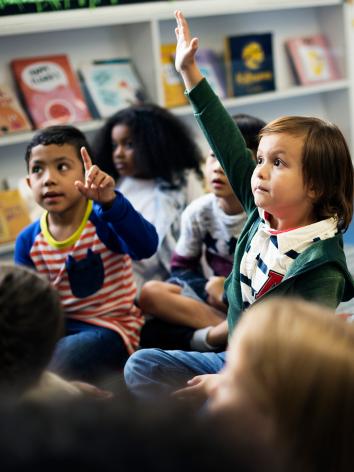 Kinderen in een kleuterklas steken hun vinger in de lucht