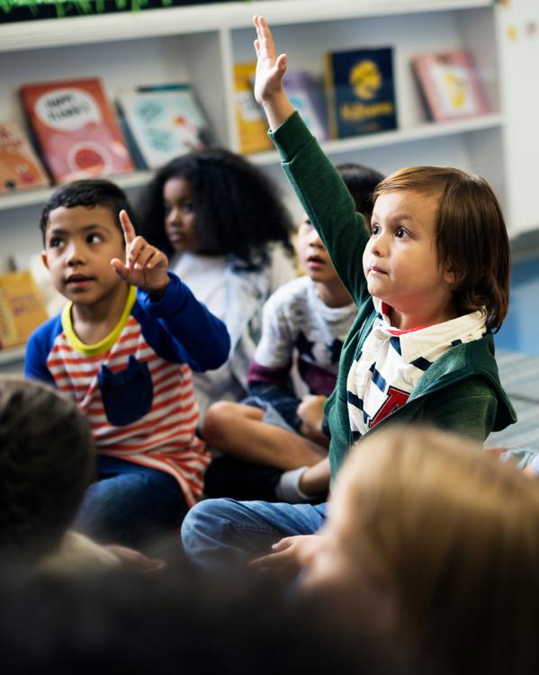 Kinderen in een kleuterklas steken hun vinger in de lucht