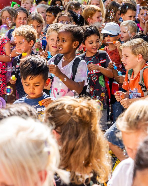 Groep basisschoolkinderen speelt buiten met bellenblaas