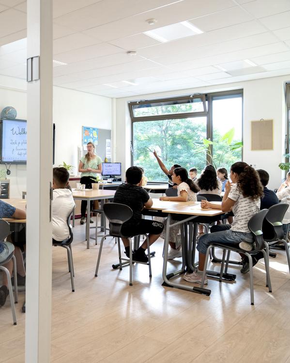 Iemand steekt zijn hand op in een vol klaslokaal