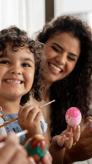 Een blij meisje houdt een beschilderd ei vast.