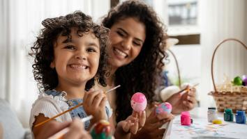 Een blij meisje houdt een beschilderd ei vast.