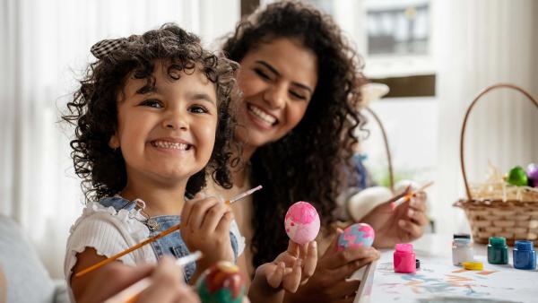 Een blij meisje houdt een beschilderd ei vast.