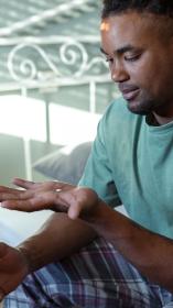 een man zit op bed en kijkt naar een pil in zijn hand