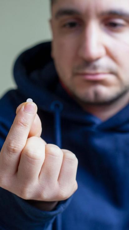 een man kijkt naar een pilletje