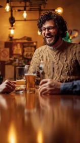 Een lachende man drinkt een biertje in zijn stamkroeg.
