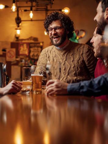 Een lachende man drinkt een biertje in zijn stamkroeg.