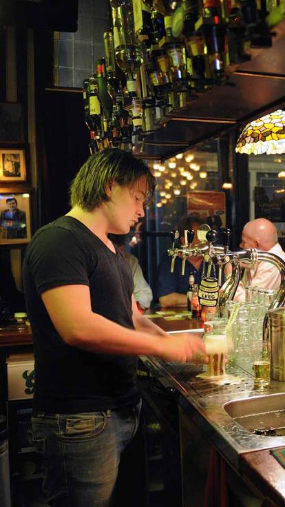 De barman roomt een biertje af.