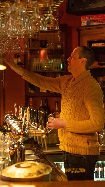 Barman ruimt de glazen boven de bar op.