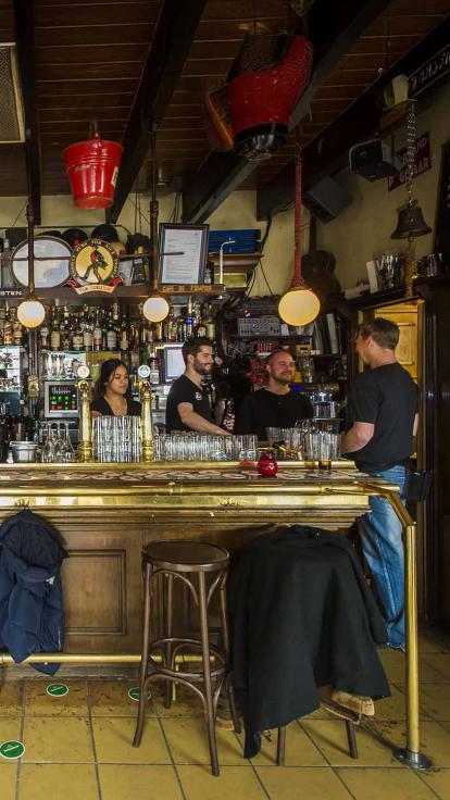 Twee mannen zitten aan de toog een biertje te drinken.