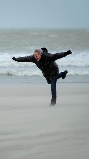 wandelaars op het strand in een storm met stevige windvlagen