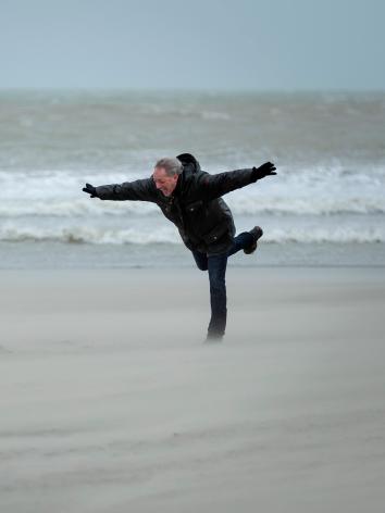 wandelaars op het strand in een storm met stevige windvlagen