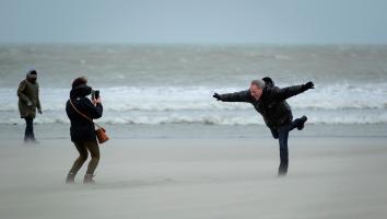 wandelaars op het strand in een storm met stevige windvlagen