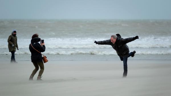 wandelaars op het strand in een storm met stevige windvlagen