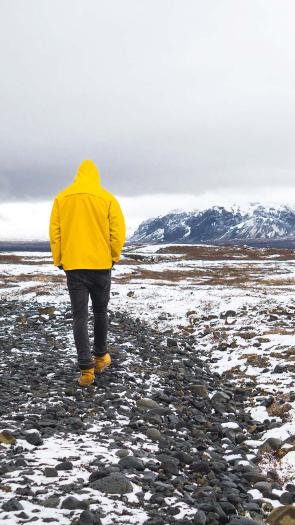 een persoon loopt in een landschap met smeltende sneeuw