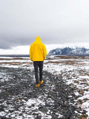een persoon loopt in een landschap met smeltende sneeuw