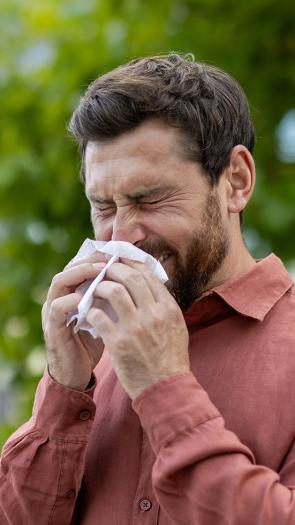 een man niest buiten in een zakdoekje