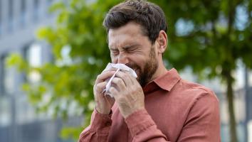 een man niest buiten in een zakdoekje