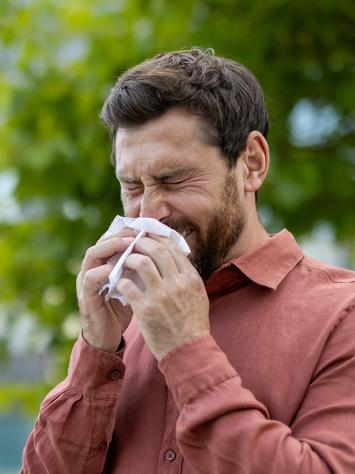 een man niest buiten in een zakdoekje