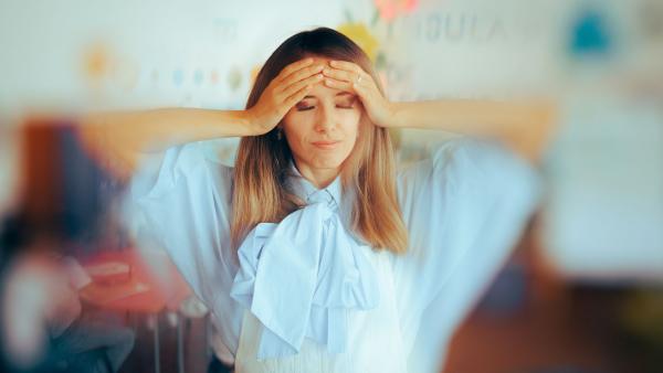 een vrouw met ogen dicht en handen op het voorhoofd in een drukke omgeving