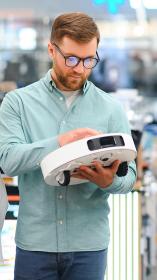 Een man en vrouw bekijken een robotstofzuiger in een winkel 