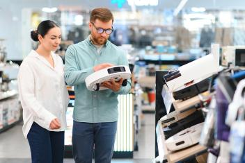 Een man en vrouw bekijken een robotstofzuiger in een winkel 