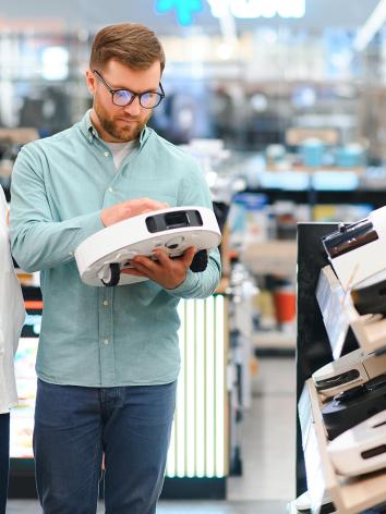 Een man en vrouw bekijken een robotstofzuiger in een winkel 