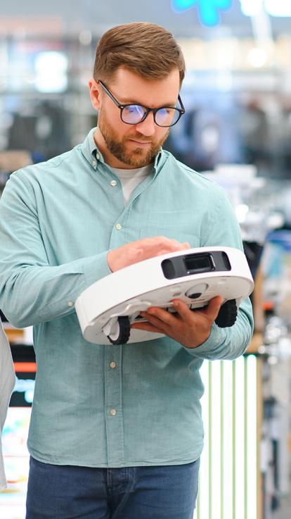 Een man en vrouw bekijken een robotstofzuiger in een winkel 