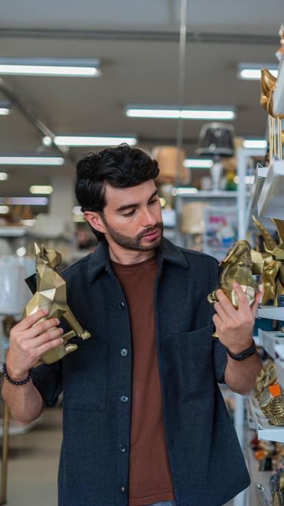Man kijkt in een winkel naar verschillende goudkleurige beeldjes van dieren