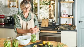 Vrouw voegt kruiden toe aan olijven in een pot