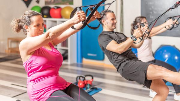 drie mensen volgen een groepsles in een fitnesszaal
