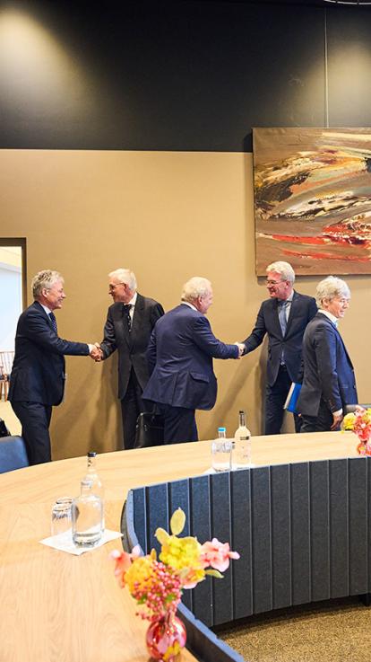 Twee formateurs schudden de hand met andere politici in pak